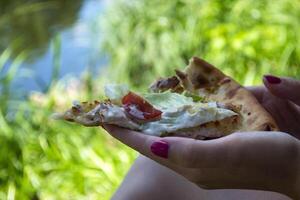 un' pezzo di Pizza nel il mani di un' donna, vicino su. foto