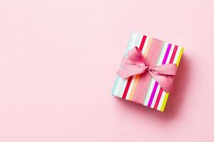 avvolto Natale o altro vacanza fatto a mano presente nel carta con rosa nastro su rosa sfondo. presente scatola, decorazione di regalo su colorato tavolo, superiore Visualizza con copia spazio foto