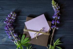 regalo scatola con saluto carta e mazzo di lupini su un' buio blu di legno sfondo. foto