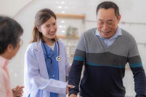 asiatico giovane infermiera supporto anziano più vecchio uomo camminare con camminatore. bellissimo infermiera Aiuto e prendere cura. anziano maturo Nonno paziente fare fisico terapia con un' gruppo di anziano amici nel Ospedale. foto