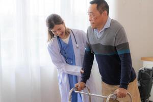 asiatico giovane infermiera supporto anziano più vecchio uomo camminare con camminatore. bellissimo infermiera Aiuto e prendere cura. anziano maturo Nonno paziente fare fisico terapia con un' gruppo di anziano amici nel Ospedale. foto