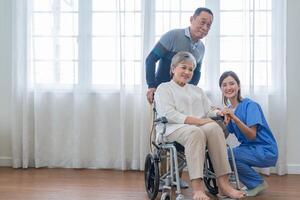 asiatico giovane infermiera supporto coppia anziano più vecchio uomo e donna nel un' sedia a rotelle. anziano maturo e un' gruppo di anziano amici vivente nel il Ospedale. socializzazione di pensionato le persone. foto