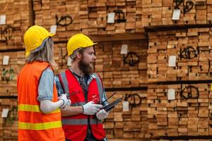 lavoratori falegname indossare sicurezza uniforme e difficile cappello Lavorando e controllo il qualità di di legno prodotti a laboratorio produzione. uomo e donna lavoratori legna nel buio magazzino industria. foto