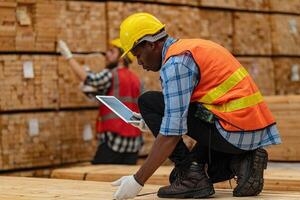 africano lavoratori uomo ingegneria a piedi e ispezionando con Lavorando suite vestito e mano guanto nel legname legna magazzino. concetto di inteligente industria lavoratore operativo. legna fabbriche produrre legna palato. foto