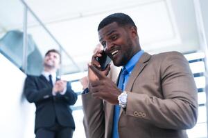 inteligente nero uomo d'affari Guardando mobile Telefono. Calvo adulto uomo indossare formale indossare. riflessivo afroamericano uomo d'affari nel un' perfettamente su misura completo da uomo in piedi nel scala nel ufficio. foto