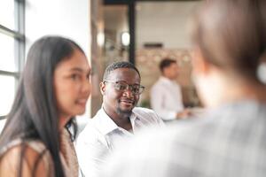 messa a fuoco di inteligente africano uomo d'affari. diverso dipendenti si riunirono nel ufficio avendo divertimento di brainstorming mentre discutere nuovo idee progetto. multirazziale collaboratori incontro a coworking spazio la zona. foto