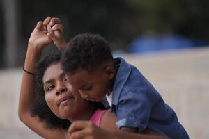 misto gara africano e asiatico madre e ragazzo è giocando a il all'aperto la zona. sorridente contento famiglia avere divertimento in esecuzione su il spiaggia. ritratto di mamma e ragazzo stile di vita con un' unico acconciatura. foto