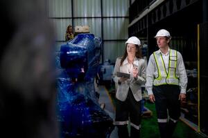 attività commerciale donna e uomo incontro e controllo nuovo macchina robot. ingegnere a piedi a magazzino industria macchina. attività commerciale trattativa concetti e tecnologia. donna è utilizzando inteligente tavoletta per presente uomo. foto