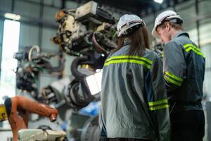 ingegneri dai un'occhiata controllo pesante macchina robot braccio. diverso squadra di industriale robotica ingegneri si riunirono in giro macchina. professionale macchinari operatori riparazione elettrico robot su luminosa digitale pannello. foto