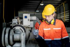 ingegnere uomo controllo il stato di macchina e Usato chiave inglese per vite alcuni parte di attrezzatura a cnc fabbrica. lavoratore indossare sicurezza bicchieri e casco. Manutenzione e riparazione concetto. foto