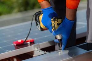 vicino su mano utilizzando trapano autista attrezzatura su struttura. ingegnere uomo è Lavorando per costruire solare pannelli sistema su tetto. installazione solare fotovoltaico pannello sistema. foto