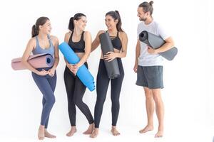 gruppo di contento sportivo donne e tipo indossare corpo elegante abbigliamento sportivo Tenere personale tappeti Appoggiato su un' bianca sfondo. in attesa per yoga classe o corpo peso classe. salutare stile di vita e benessere foto