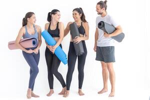 gruppo di contento sportivo donne e tipo indossare corpo elegante abbigliamento sportivo Tenere personale tappeti Appoggiato su un' bianca sfondo. in attesa per yoga classe o corpo peso classe. salutare stile di vita e benessere foto