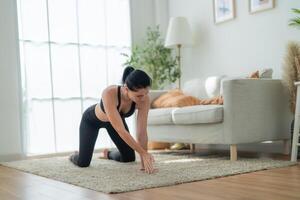 vicino su donne fiducioso formazione yoga. atletico donne nel abbigliamento sportivo fare fitness allungamento esercizi a casa nel il vivente camera. sport e ricreazione concetto. yoga insegnante è porzione ragazza. foto