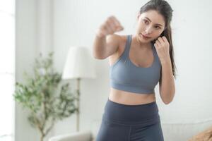 attraente e forte donna allungamento prima fitness a interno Casa. salutare stile di vita. donna caldo su di boxe nel il aria. giovane femmina con sottile corpo punzonatura boxe gioco di gambe cardio esercizio. foto