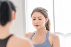 Due donne fiducioso formazione yoga. atletico donne nel abbigliamento sportivo fare fitness allungamento esercizi a casa nel il vivente camera. sport e ricreazione concetto. yoga insegnante è porzione giovane donna. foto