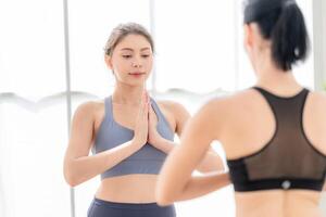 Due donne fiducioso formazione yoga. atletico donne nel abbigliamento sportivo fare fitness allungamento esercizi a casa nel il vivente camera. sport e ricreazione concetto. yoga insegnante è porzione giovane donna. foto