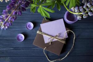 regalo scatola con saluto carta e mazzo di lupini su un' buio blu di legno sfondo. foto
