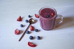 il frutta frullato nel un' bicchiere tazza, e maturo frutta su il tavolo. foto