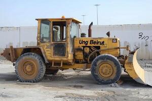 beige giallo classificazione macchina parcheggiata nel industriale la zona di Arabia arabia, circondato di calcestruzzo lotto e bianca muri foto