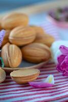 biscotti nel il modulo di conchiglie su un' tovaglia con fiori foto