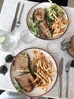 panini con formaggio, lattuga, pomodoro e francese patatine fritte nel un' ristorante foto