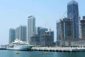 un' lusso yacht ancorato nel davanti di il vivace costruzione siti di nuovo grattacielo edifici a dubai marina. dubai, Emirati Arabi Uniti - agosto 15, 2023 foto