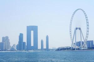 il dubai Ferris ruota sta alto sotto il luminosa sole, con calma acque nel il primo piano. dubai, Emirati Arabi Uniti - agosto 15, 2023 foto