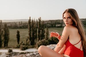 bene guardare mezzo anziano donna con lungo capelli, fitness istruttore nel ghette e cime fare allungamento e pilates su il roccia vicino foresta. femmina fitness yoga routine concetto. salutare stile di vita foto