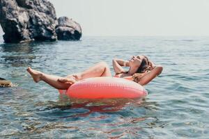 donna estate mare. contento donna nuoto con gonfiabile ciambella su il spiaggia nel estate soleggiato giorno, circondato di vulcanico montagne. estate vacanza concetto. foto