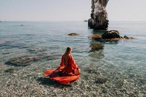 donna viaggio mare. contento turista nel rosso vestito godere assunzione immagine all'aperto per ricordi. donna viaggiatore in posa su il roccia a mare baia circondato di vulcanico montagne, condivisione viaggio avventura viaggio foto