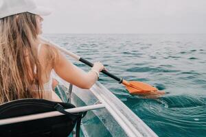 donna nel kayak indietro Visualizza. contento giovane donna con lungo capelli galleggiante nel trasparente kayak su il cristallo chiaro mare. estate vacanza vacanza e allegro femmina persone rilassante avendo divertimento su il barca foto