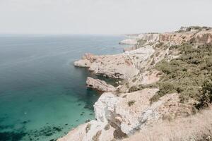 aereo Visualizza a partire dal sopra su calma azzurro mare e vulcanico roccioso sponde. piccolo onde su acqua superficie nel movimento sfocatura. natura estate oceano mare spiaggia sfondo. nessuno. vacanza, vacanza e viaggio concetto foto