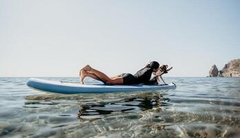 mare donna sup. silhouette di contento positivo giovane donna con sua cane, fare surf su cenare tavola attraverso calma acqua superficie. idilliaco tramonto. attivo stile di vita a mare o fiume. estate vacanza con animali domestici. foto