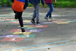 avvicinamento di bambini piedi salto e giocando campana nel scuola cortile foto