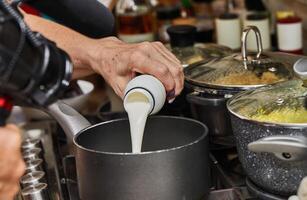 talentuoso capocuoco accuratamente crea un' delizioso lotto di cioccolato mousse nel il comfort di il tuo casa cucina, scrosciante il crema in un' padella per creare un' ricco, cremoso dolce foto