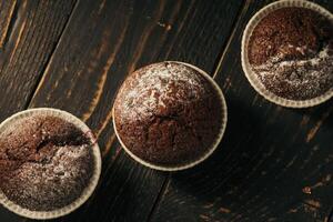 cioccolato muffin con in polvere zucchero su un' nero sfondo. ancora vita vicino su. buio lunatico. cibo foto. foto