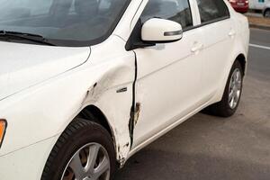 danneggiato lato porta su un' bianca auto dopo un' piccolo traffico incidente richiedendo un' riparazione foto