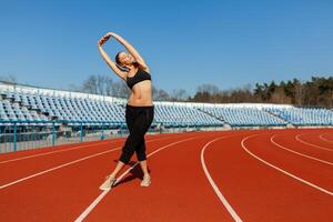giovane fitness donna corridore caldo su prima in esecuzione su traccia. mattina esercizi a estate foto