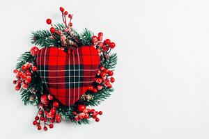 Natale decorativo ghirlanda di agrifoglio, edera, vischio, cedro e leyland foglia rametti con rosso frutti di bosco al di sopra di bianca sfondo. foto