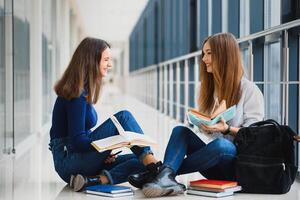 femmina studenti seduta su il pavimento e lettura Appunti prima esame foto