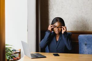 difficile opera assicura successo. concentrato giovane africano donne Lavorando su il computer portatile mentre seduta a Lavorando posto foto