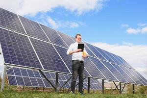 solare energia. giovane attività commerciale uomo nel un' bianca camicia vicino il solare pannelli per energia impianti. foto