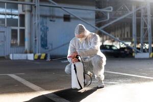 uomo vestito bianca protettivo tuta da lavoro spruzzatura superficie antibatterico disinfettante spruzzatore durante quarantena foto