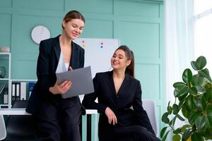 giovane donne capi siamo controllo finanziario dichiarazioni a partire dal carta documenti. Due femmina fiducioso attività commerciale lavoratore vestito nero completo da uomo nel ufficio controllo finanziario documento foto