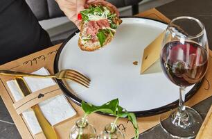 un' elegante hostess nel un' moderno cucina elegantemente posti un' delizioso piatto di carpaccio su pane su un' pulito marmo controsoffitto, dimostrando il arte di presentazione e culinario abilità foto