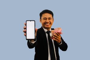 adulto asiatico uomo sorridente contento mentre mostrando vuoto mobile Telefono schermo e Tenere carta i soldi foto