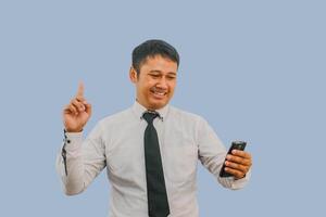 adulto uomo mostrando contento espressione con dito puntamento su quando Tenere mobile Telefono foto