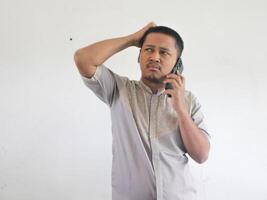 asiatico uomo Tenere il suo mobile Telefono con grave espressione foto