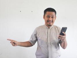 asiatico uomo Tenere il suo mobile Telefono con grave espressione foto